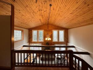 a living room with a wooden ceiling and a staircase at Modern Getaway cabin, sleeps 7 Near Meadville in Guys Mills