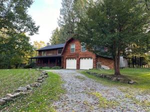 a barn with two white garage doors and a tree at Weekend Getaway, Family vacation comfort cabin in Guys Mills