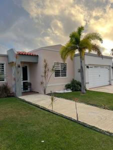 a white house with a palm tree and a driveway at La Casandra Beach House in Isabela