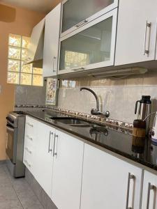 una cocina con armarios blancos y fregadero en Casa de dos plantas, en Mercedes