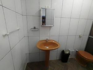 La salle de bains est pourvue d'un lavabo en bois et de toilettes. dans l'établissement Home Enseada Beach, à Guarujá