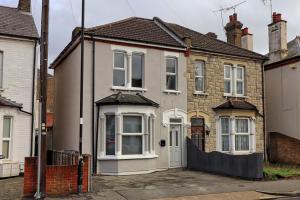 a white house with a fence in front of it at Beautiful Spacious four bedroom house with parking for 2 cars, 5 minute walk to southend station in Southend-on-Sea