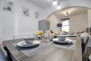 a dining room with a wooden table with plates and glasses at Beautiful Spacious four bedroom house with parking for 2 cars, 5 minute walk to southend station in Southend-on-Sea