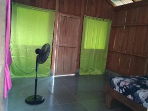 Habitación con ventilador en una habitación con cortinas verdes en Casa jungla bahía Drake, en Drake
