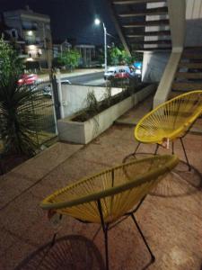 dois bancos amarelos sentados num passeio à noite em Excelente ubicación!!! em Montevidéu