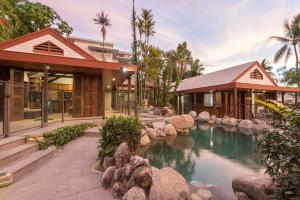 una casa con un estanque delante de un edificio en 10 Wharf Street - a tropical family home, en Port Douglas