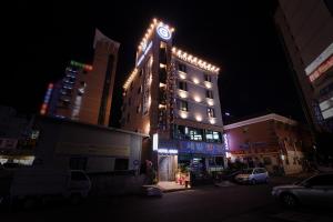 a tall building with a neon sign on it at night at Hotel Gray in Changwon