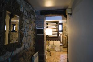 Habitación con pared de piedra y pasillo con lámpara. en Posada la Estela de Barros en Los Corrales de Buelna