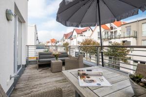 um pátio com uma mesa e um guarda-sol numa varanda em NeysTime em Norderney