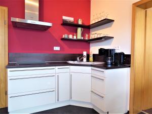 Una cocina con gabinetes blancos y una pared roja. en Cityview Winterberg Ferienwohnung in der City, en Winterberg