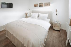 ein weißes Bett mit weißer Bettwäsche und Kissen in einem Zimmer in der Unterkunft Haus Salz & Sand Whg Sand in Norderney