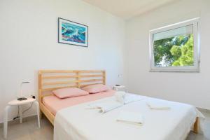 a white bedroom with a bed and a window at Seaside secluded apartments Cove Sutmiholjska, Mljet - 22318 in Blato