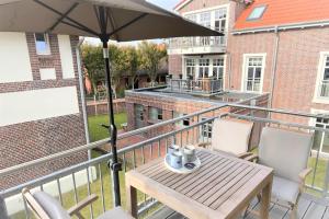 a balcony with a table and an umbrella at Ferienwohnung Inselherz in Wangerooge