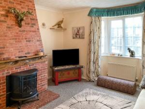 salon z ceglanym kominkiem i telewizorem w obiekcie Walnut Cottage w mieście Long Melford