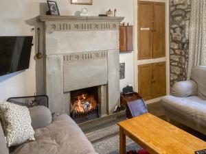 a living room with a fireplace and a couch at Spoutscroft Cottage in Austwick