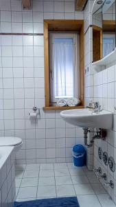 a white tiled bathroom with two sinks and a window at FEWO Marion in Oberstaufen