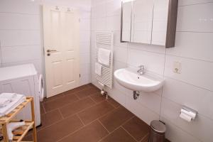 La salle de bains blanche est pourvue d'un lavabo et d'un miroir. dans l'établissement Up Warft - West, à Krummhörn