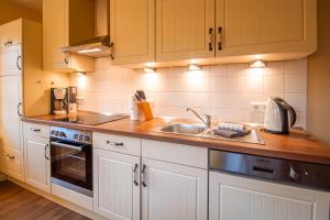 a kitchen with white cabinets and a sink at Int Hörn 2 EG in Krummhörn