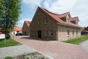 a large brick building with a red roof at Int Hörn 1 EG in Krummhörn