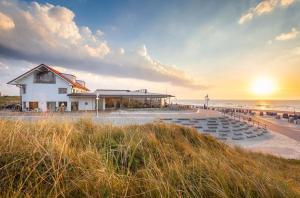 a building on the beach with the sunset in the background at Cornelius-05 in Norderney