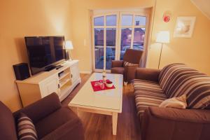 a living room with two couches and a television at Int Hörn 8 OG in Krummhörn
