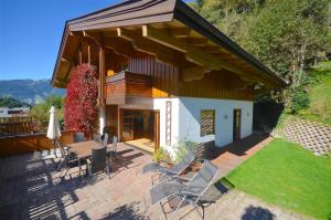 a house with a patio with chairs and an umbrella at Haus Thumersbach - by Alpen Apartments in Zell am See