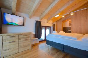 Ski-in Ski-out Chalet Maiskogel 13B - by Alpen Apartments في كابرون: غرفة نوم مع سرير وتلفزيون على الحائط