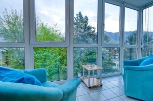 salon z dużymi oknami i niebieskimi krzesłami w obiekcie Apartment Tini - by Alpen Apartments w mieście Zell am See