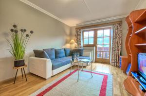 Una sala de estar con un sofá azul y un televisor. en Select Top 4 - by Alpen Apartments, en Piesendorf