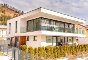 a house in the mountains with a fence at Sonnenhaus A - by Alpen Apartments in Zell am See