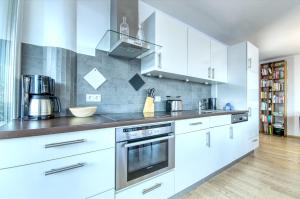 uma cozinha com armários brancos e um forno com placa de fogão em APT Super Zell -by Alpen Apartments em Zell am See