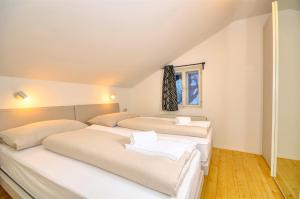 two beds in a room with white walls at Mozart Top 3 - by Alpen Apartments in Zell am See