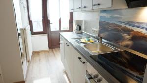 una cocina con fregadero y una pintura en la pared en Eva, en Tönning 10 fotos más