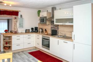 a kitchen with white cabinets and a red rug at Apartment Birke 3 - by Alpen Apartments in Bad Gastein