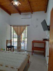 une chambre avec deux lits et une télévision et une fenêtre dans l'établissement Casa de descanso y naturaleza, à Paso de la Patria