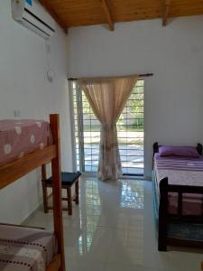 Cette chambre comprend deux lits et une fenêtre avec un rideau. dans l'établissement Casa de descanso y naturaleza, à Paso de la Patria