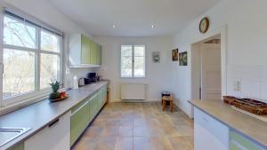 a kitchen with green and white cabinets and a tile floor at FeWo Am Wald in Boek