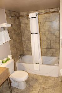 a bathroom with a toilet and a tub and a sink at Travelodge by Wyndham Swift Current in Swift Current