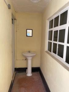 a bathroom with a white sink and two windows at Hostal Las Quince Letras in Tehuacán