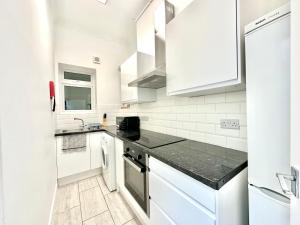 eine Küche mit weißen Schränken und einer schwarzen Arbeitsplatte in der Unterkunft The Euston Guest House-64 in London