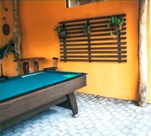 a pool table in a room with an orange wall at Pousada Meu Xodó in São Miguel dos Milagres