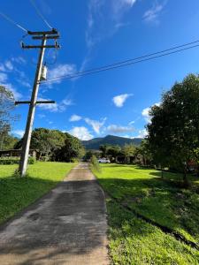 a road with a utility pole and a green field at Angha forest view บ้านกลางนา in Ban Sop Mae Klang