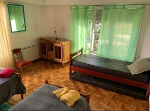 1 Schlafzimmer mit 2 Betten und einem Fenster mit grünen Vorhängen in der Unterkunft Playa Grande in Mar del Plata