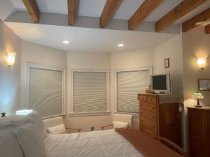 a bedroom with a bed and a tv and windows at High Hill Inn in Montpelier