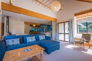 a living room with a blue couch and a table at Ridge Retreat in Rotorua