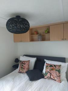 ein Bett mit zwei Kissen und einer Lampe darüber in der Unterkunft Camping 't Venhop in Berkhout
