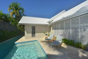 een achtertuin met een zwembad en twee stoelen en een huis bij Tropical Villa on Craven Close in Port Douglas
