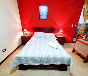 1 dormitorio con una pared roja, 1 cama y 2 lámparas en Beautiful view suite Suite vista hermosa en Macas
