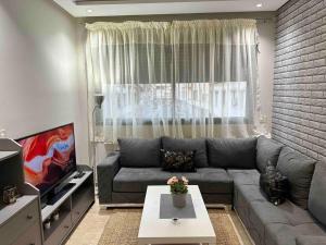 a living room with a gray couch and a window at Racine Studio bd Anfa in Casablanca