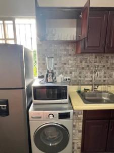 a kitchen with a microwave on top of a washing machine at City suite sosua A in Sosúa